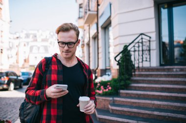 Sıcak içeceği olan adam akıllı telefon kullanıyor.