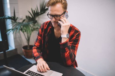 Laptop kullanan ve kafede telefonla konuşan ciddi bir serbest yazar.