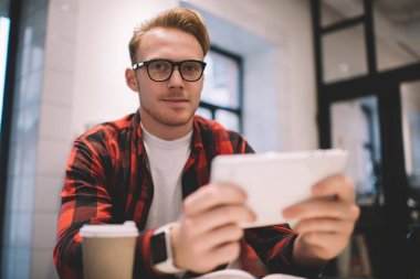 Tabletli adam kameraya bakıyor.