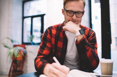 Kafede notlar alan düşünceli bir adam.