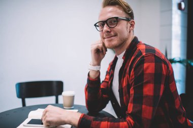 Kafe masasında akıllı telefon kullanarak gülümseyen serbest çalışan.