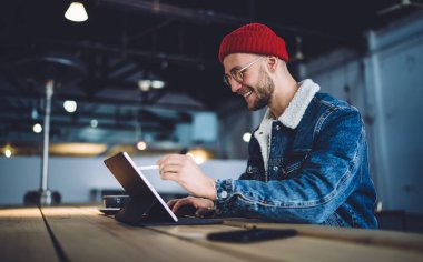 Tablet dokunmatik ekran cihazına resim çizmek için akıllı stil kullanan neşeli erkek sanatçı birlikte çalışma alanında 4G kablosuz, modern teknoloji ile uzaktan çalışan yetenekli grafik tasarımcısı