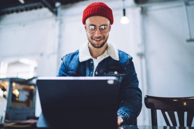 Genç, beyaz bir öğrenci elektronik aletle posta mesajlarını kontrol ediyor. Wi-Fi 'ye bağlı, mutlu hippi adam evde oturup beklediği için dokunmatik bloknotla eğleniyor.