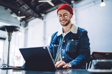 Görme düzeltmesi için optik gözlüklü beyaz bir öğrenci. Elektronik aletle posta mesajlarını kontrol ediyor. Kablosuz internete bağlanıyor.