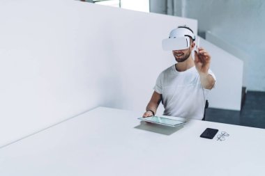 Sanal gerçeklik kulaklığı takan neşeli erkek mimar modern ofiste çalışırken 360 derece panorama tasarım inşaat projesi yapıyor, gözlüklü yetenekli bir adam 3D boyut veya daldırma yaratıyor.