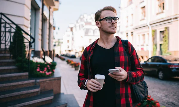 Thoughtful man with hot drink and smartphone looking away — Stock Photo, Image