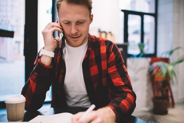 Homem falando por telefone e fazendo notas no café — Fotografia de Stock