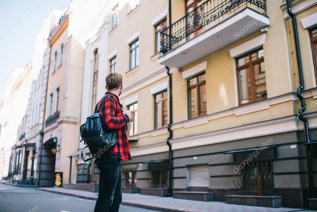 Anonymous man with backpack standing on street