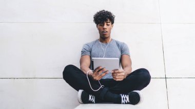 Gündelik giysiler içinde yakışıklı hippi adam sosyal reklamcılık için fotokopi alanı olan şehir ortamında blog yazarları için online webinar izliyor, promosyon geçmişine yakın milenyum adamı