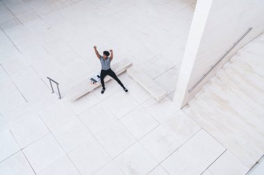 Gündelik giyinen mutlu adam, modern dizüstü bilgisayarla geliştirilen başlangıç projesinin bitmesinden çok memnun. Uzaktan kumandayı kutlayan elini kaldırmış başarılı Latin erkek serbest yazar.