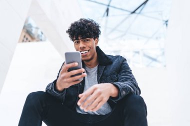 Şehir merkezinde dinlenen neşeli hipster adamın portresi ve hızlı internet bağlantısı olan akıllı telefon aygıtı, sohbet etmek için cep telefonu tutan pozitif milenyum insanı.