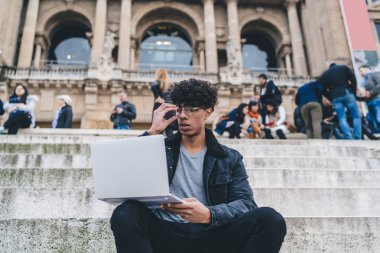 Barcelona 'daki Montjuic binası yakınlarında çalışan Latin erkek dijital göçebe bir sonraki seyahat için internet sitelerinde ucuz uçuş biletleri arıyor, gözlüklü yetenekli adam.