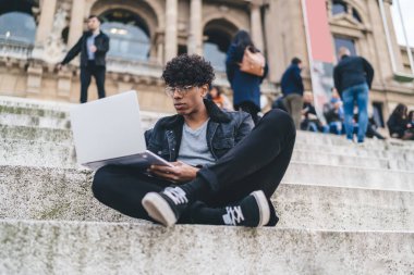 Klasik optik gözlüklü, düşünceli hippi adam gezintiden sonra Barcelona rehber bilgisi okuyan, uzaktan çalışan erkek dijital göçebe.