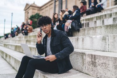 Moda kıyafetli tefekkür adamı, modern dizüstü bilgisayarla iş projesinin detaylarını tartışan uluslararası bir cep telefonu çağrısı aldı. Düşünceli erkek dijital göçebe, gezinen 4G kullanıyor.