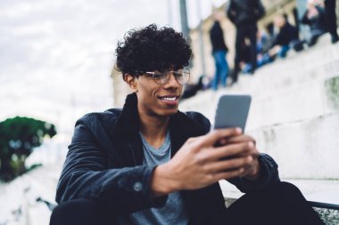 Neşeli seyahat blogcusu, İspanyol tatilleri hakkında sosyal takipçilerle sanal iletişimde eğleniyor. Açık havada dinlenirken posta kontrol etmek için 4G kablosuz internet kullanan yakışıklı bir adam.