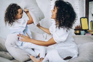 Anne ve kızı yastık savaşı yapıyor.