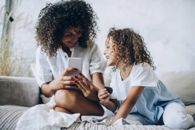 Evde telefonla konuşan kızıyla takılan bir kadın.