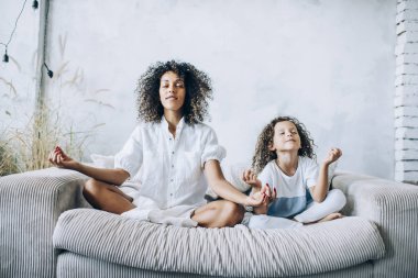 Sevimli kız ve anne kanepede meditasyon yapıyor. 