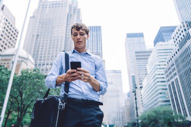 Resmi olarak genç işverenin görünüşünün altında, şehir merkezindeki şehir merkezinde bulunan modern cep telefonunda SMS mesajı okuyor ve iş arkadaşlarıyla iletişim kurmak için 4G kablosuz internet bağlantısı kullanıyor