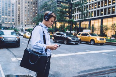 Modern cep telefonu cihazıyla ses mesajlarını kontrol eden zeki bir adamın yan görüntüsü gürültü önleyici kulaklıklar, web sitesinde evrak çantası arama metniyle beyaz erkek çalışan