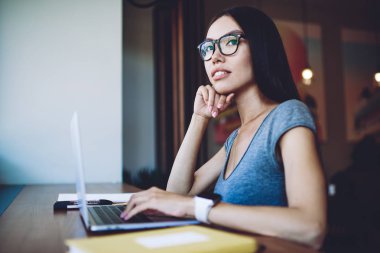 Optik gözlüklü düşünceli kadın gazeteci web dergisi için metin makalesi üzerinde kafa yoruyor. Kafkasyalı hippi kız birlikte çalıştığı yerdeki dizüstü bilgisayardan bir şeyler öğrenirken dikkatli bakıyor.