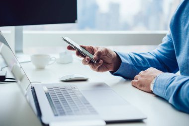 Modern iş adamı masada akıllı telefon kullanıyor.