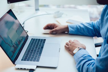 Ekin adam dizüstü bilgisayarında çizelgelerle çalışıyor.