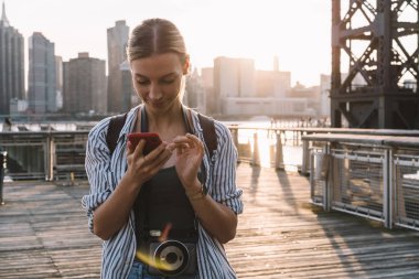 Beyaz amatör fotoğrafçı boynundaki eski fotoğraf makinesiyle Amerikan bayramları hakkında yazı yazıyor. Manhattan 'lı bin yıllık kadın turist sanal internet iletişiminin keyfini çıkarıyor.