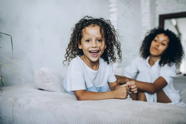 Smějící se šťastná dívka s matkou na pohovce — Stock fotografie