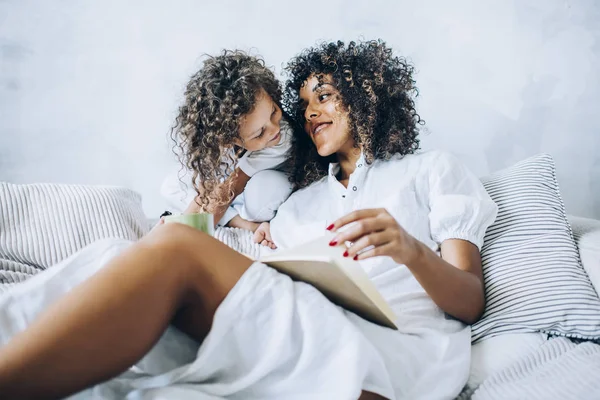 Cuddling woman and girl on couch at home — Stock Photo, Image