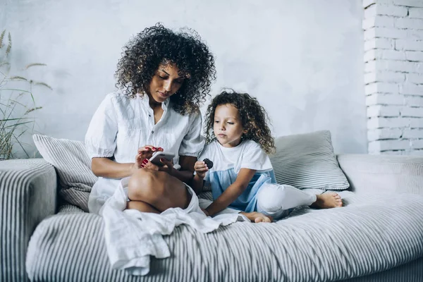 Menina encantadora com a mãe usando telefone celular — Fotografia de Stock