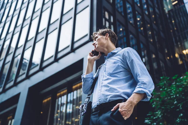 Below view of businessman making online international cell conversation for discussing corporate productive plan standing outdoors in downtown, Caucasian male trader talking with friend during break