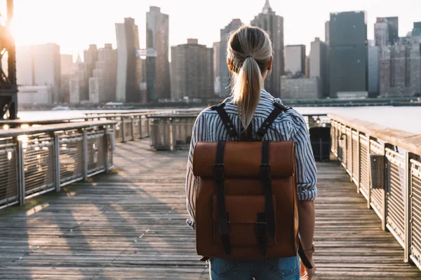 旅行时带着旅行包的时尚女性游客的背景图 站在美国城市的背景下 审视曼哈顿地区的地标 千禧年女性在旅行中探索美国 — 图库照片
