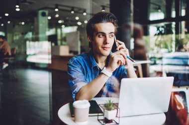 Akıllı telefondan konuşan sıradan giyinmiş hippi bilgisayarla iş yerinde oturup önemli bilgileri tartışıyor. Genç adam danışmanlık için müşteri hizmetlerini arıyor.
