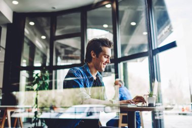 Bin yıllık neşeli hippi adamın kafeteryadaki internet bloguna bağlı takipçilerle sohbet ederken kendini iyi hissetmesi kafeteryada şakalar arayan mutlu bir adam.