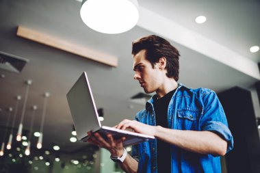 Kafası karışmış beyaz erkek yazılım geliştirici elinde dizüstü bilgisayarla veritabanını güncellemek için program kodu üzerinde kafa yoruyor, ciddi bir adam elinde netbook tutuyor tanıtım alanında 4G kablosuz internete bağlı