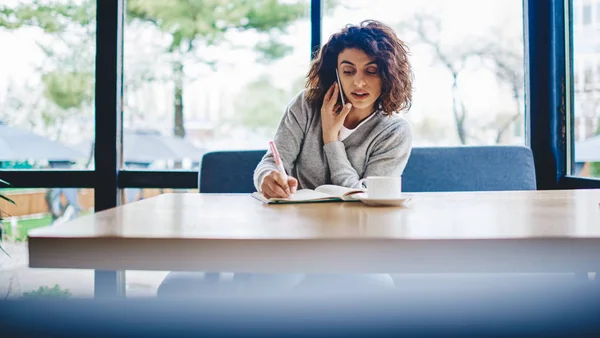 Caucasian Young Woman Making Notes Notepad While Talking Mobile Operator — Stock Photo, Image