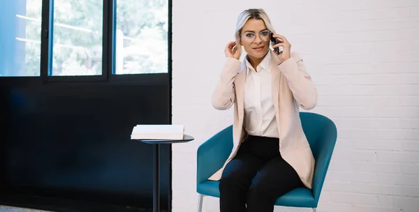 执行经理与同事交谈时 她用智能手机应用于商务电话 描绘了一位戴着时髦眼镜 迷人的高加索女企业家的形象 以进行视力矫正 — 图库照片