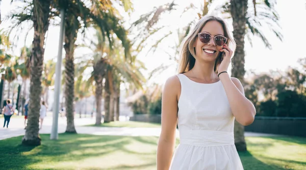 Smiling woman chatting on phone on sunny street — Stock Photo, Image