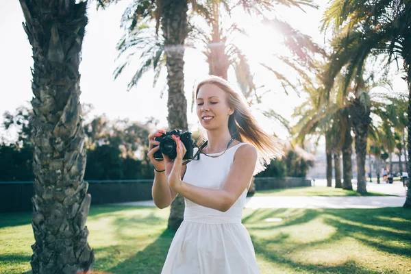 Glimlachende vrouw met fotocamera op zonnige straat — Stockfoto