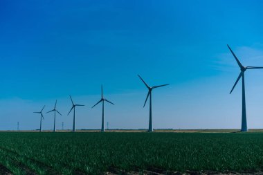 Metal modern yel değirmenleri temiz rüzgar gücüyle dönüyor yenilikçi çiftlikte alternatif enerji sağlayan elektrik üretiyorlar. Alternatif elektrik üretimi 