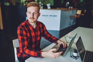 Düşünceli erkek yazılım geliştirici, internet sağlayıcısından telefon beklerken modern ağ kitabıyla oturmuş yeni bir antivirüs uygulaması düşünüyor, hipster adam uzaktan çalışıyor.