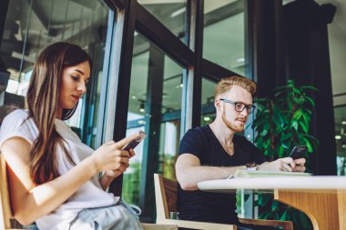 Yoğunlaşmış erkek ve kadın internete girip çevrimdışı diller öğrenmek için yeni uygulamalar arıyor, milenyum erkek ve kadın hipsterleri sohbet etmek için akıllı telefon cihazlarıyla wifi 'ye bağlanıyor
