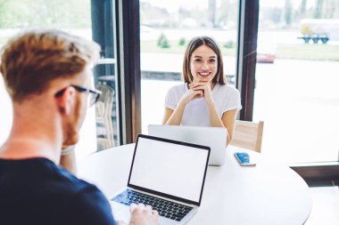 Yüzünde şirin bir gülümseme olan dizüstü bilgisayarla masada oturan neşeli yeniyetme kız portresi, internet reklamınız için boş ekranlı modern bilgisayarla bilgi arayan genç adam.