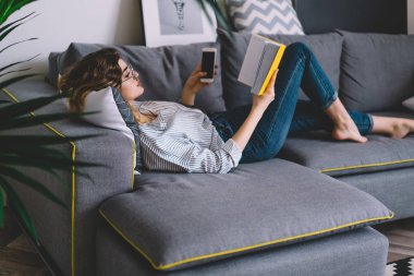 Akıllı kadın rahat koltukta uzanıyor ve kendi odasında ilginç kitaplar okuyor. Beyaz tenli hippi kız elinde akıllı telefon tutuyor ve boş zamanlarında koltukta dinlenerek en çok satan kitaplardan zevk alıyor.
