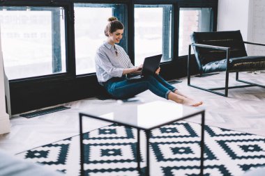 Mutlu gülümseyen yeniyetme kız internet sitesinde komedi içerikli komik bir film izlerken kendi evinde yerde oturuyor ve interneti taramak için modern netbook 'ta 4G kablosuz internet kullanıyor.