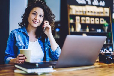 Güzel amatör fotoğrafçı, kafeteryanın içinde çalışırken eski moda fotoğraflar sattığı için büyük şirkete telefon ediyor. Çekici bir kadın cep telefonuyla iş arkadaşıyla konuşuyor.