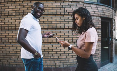 Bağımlı kadın blogcuların yanında yürüyen neşeli, esmer, hippi bir adamın portresi. Takipçilerden gelen mesajları kontrol ediyor. Mutlu adam hayattan zevk alıyor.