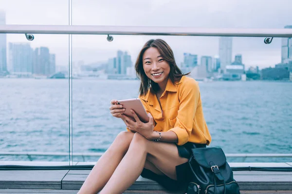 現代のデジタルタブレットを手にした幸せなヒップスターの女の子の肖像都市の設定に座って 仮想友人とオンライン通信中にカメラで笑って 中国の技術を使用して千年 — ストック写真