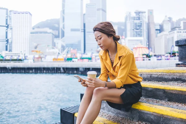 通过在现代手机小玩艺儿上的定位应用 从侧面看千年女性一代在时尚服装打字文本中的搜索目的地 亚洲游客在咖啡休息时间使用4G互联网 — 图库照片